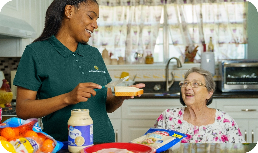 Caregiver making a sandwich for an elderly woman